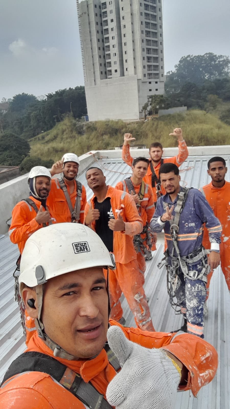Equipe de pintura predial certificada em trabalho em altura, com capacetes e equipamentos de segurança